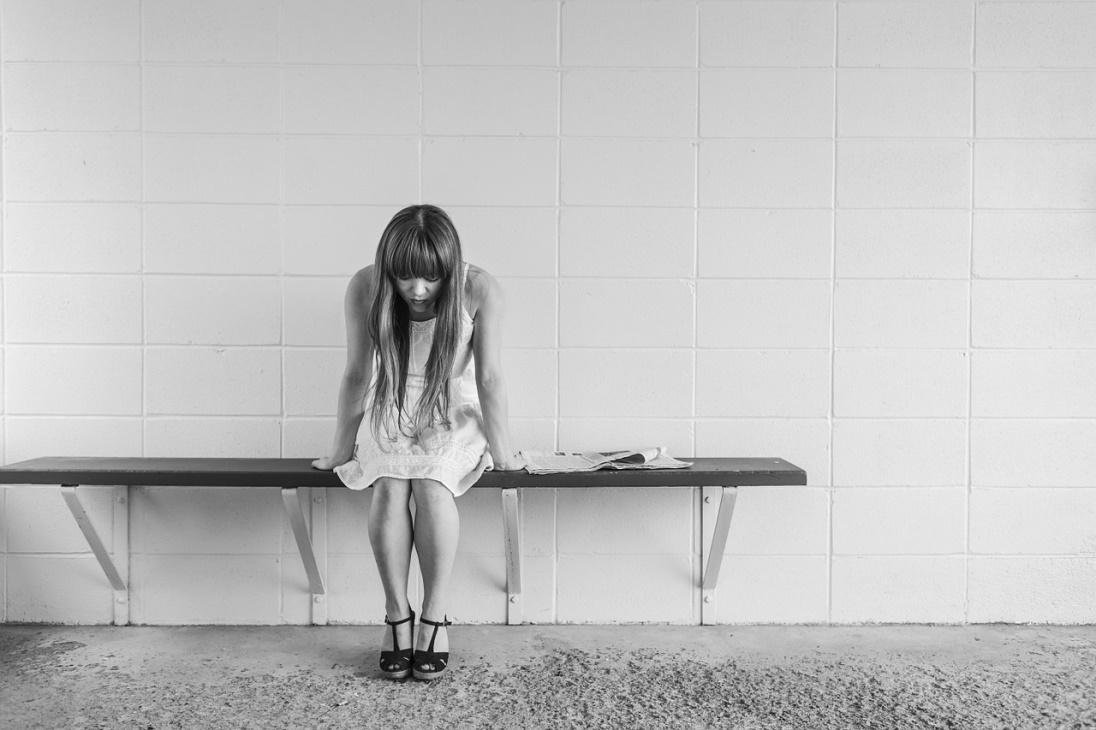 Worried girl at treatment center sitting on bench