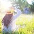 woman sitting in field of flowers with straw hat on